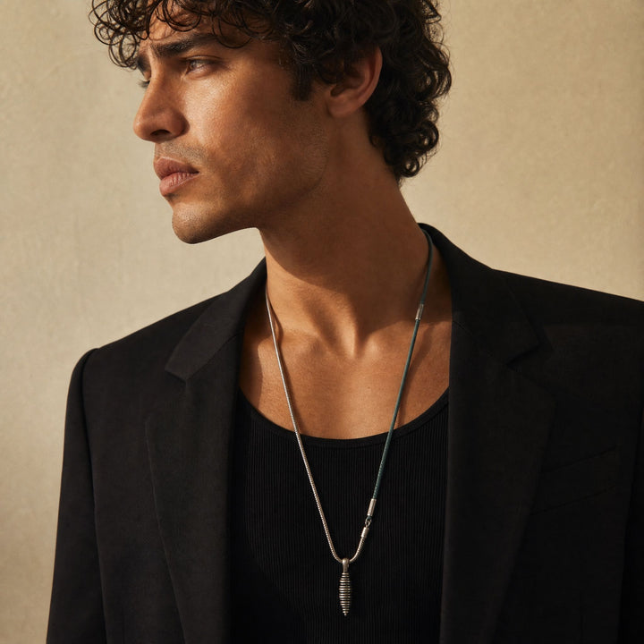 Model wearing the Acies Cocoon Pendant in oxidized silver with green enamel and green leather.