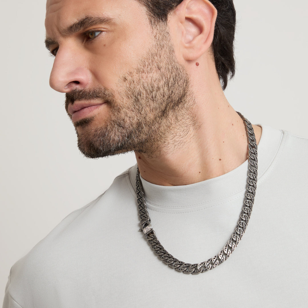 Man wearing an ornate dark chain necklace.