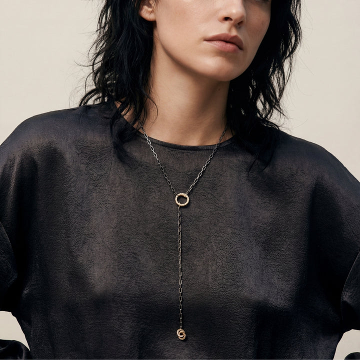 Portrait shot of Y-necklace styled with a dark silk top.