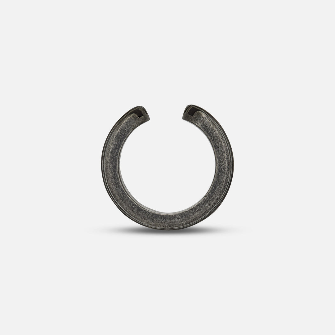 Planar shot of open ear cuff highlighting split terminal over matte floor.