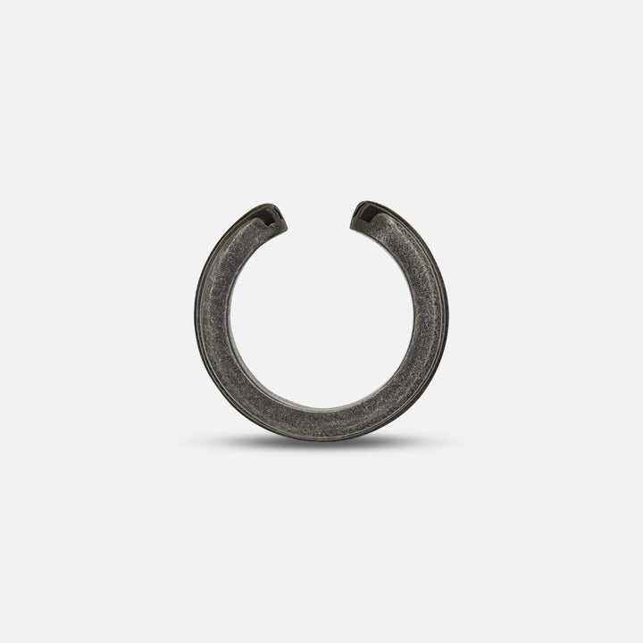 Planar shot of open ear cuff highlighting split terminal over matte floor.
