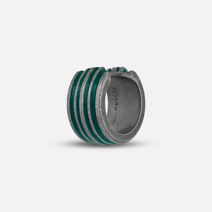 Grooved ring in textured silver and emerald enamel on plain backdrop.