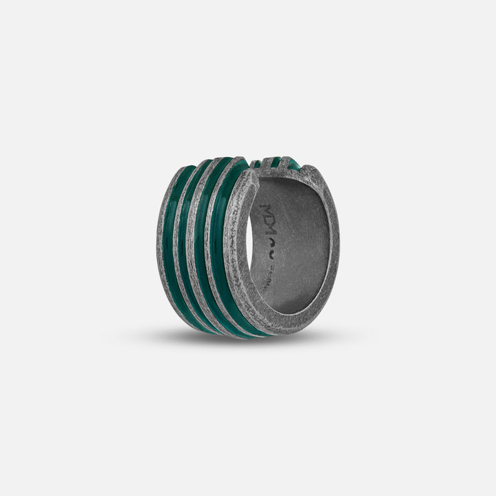 Grooved ring in textured silver and emerald enamel on plain backdrop.
