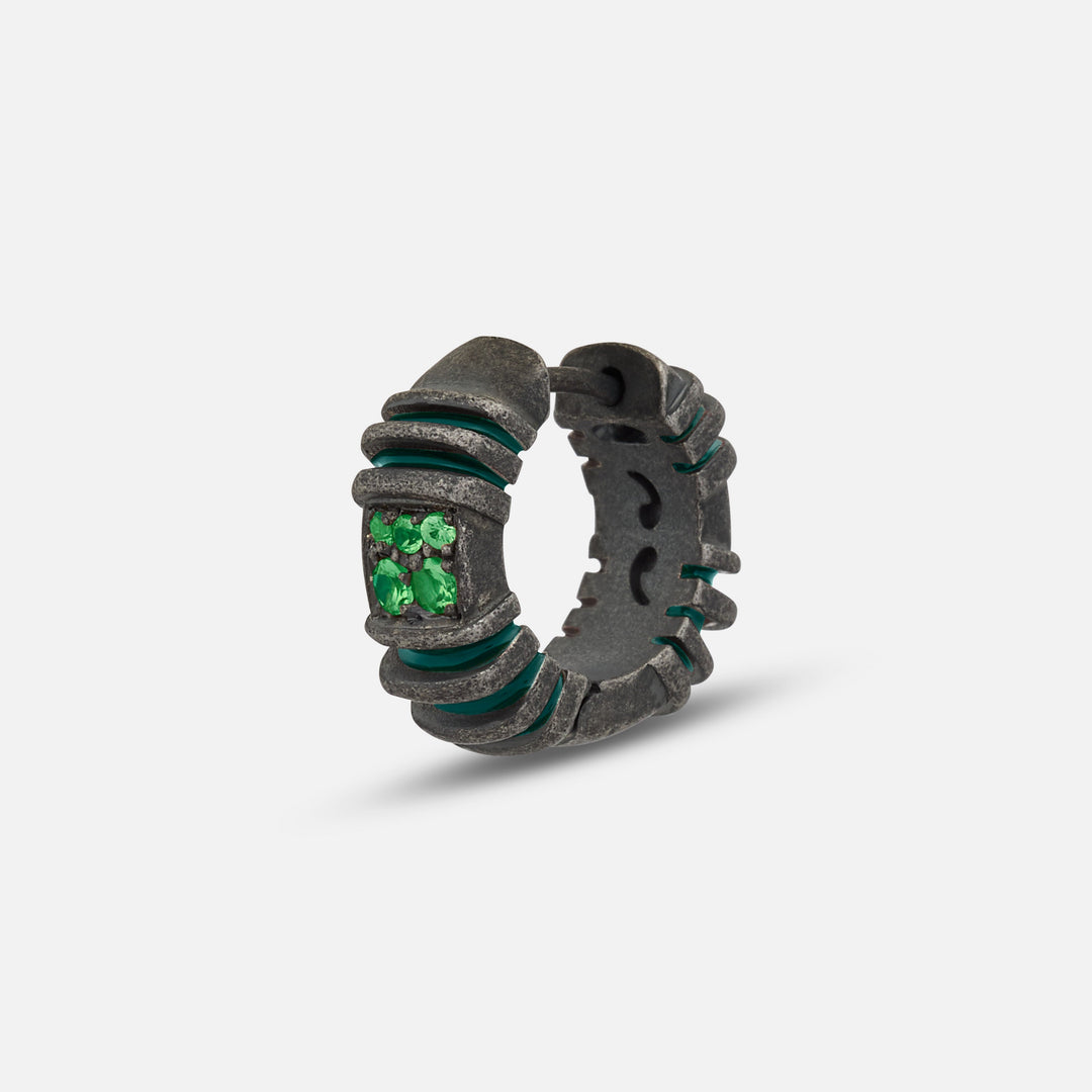 Small hoop in blackened metal and emerald stones on a bright stage.