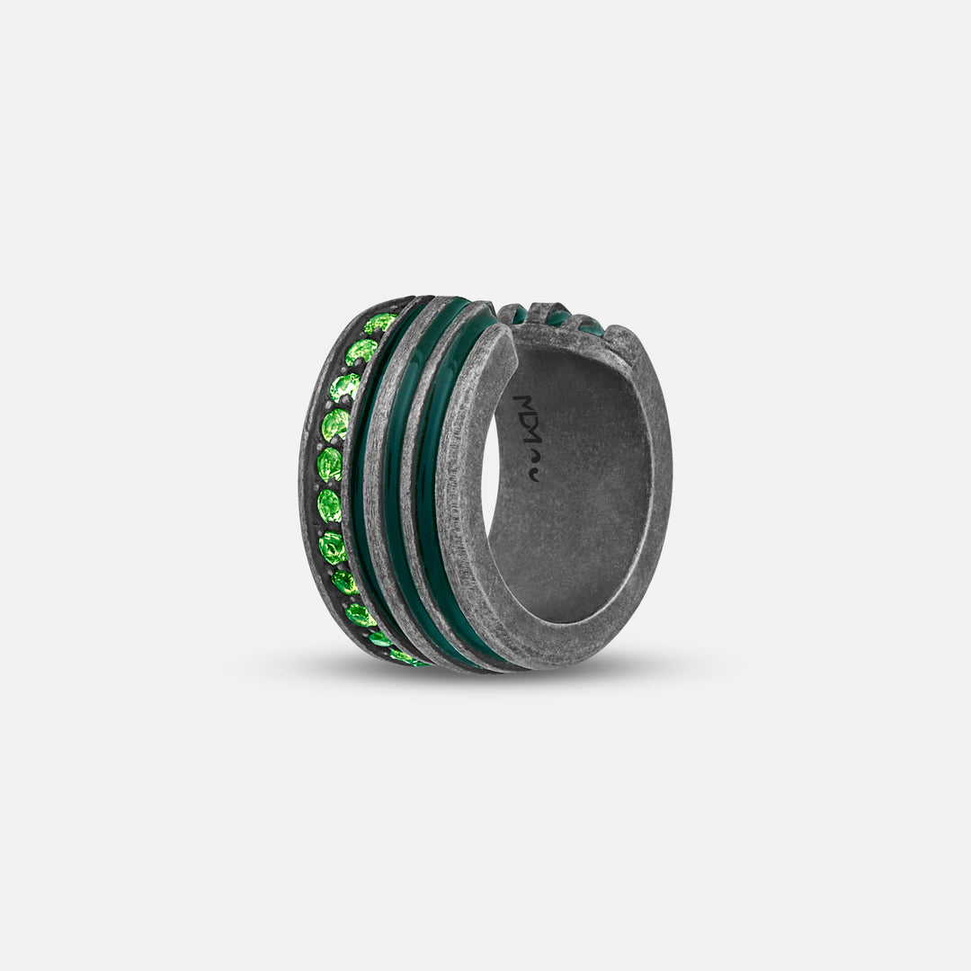 Wide band ring in distressed silver and green stones on a plain gray backdrop.