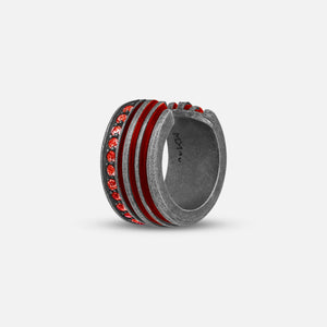 Thick ring in dark metal and red stones on a clean background.