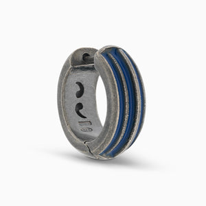 MARCO DAL MASO ACIES Huggie Earring in oxidized silver with contrasting blue enamel stripes, featuring a curved hoop design, shown in an angled product view against a light background.