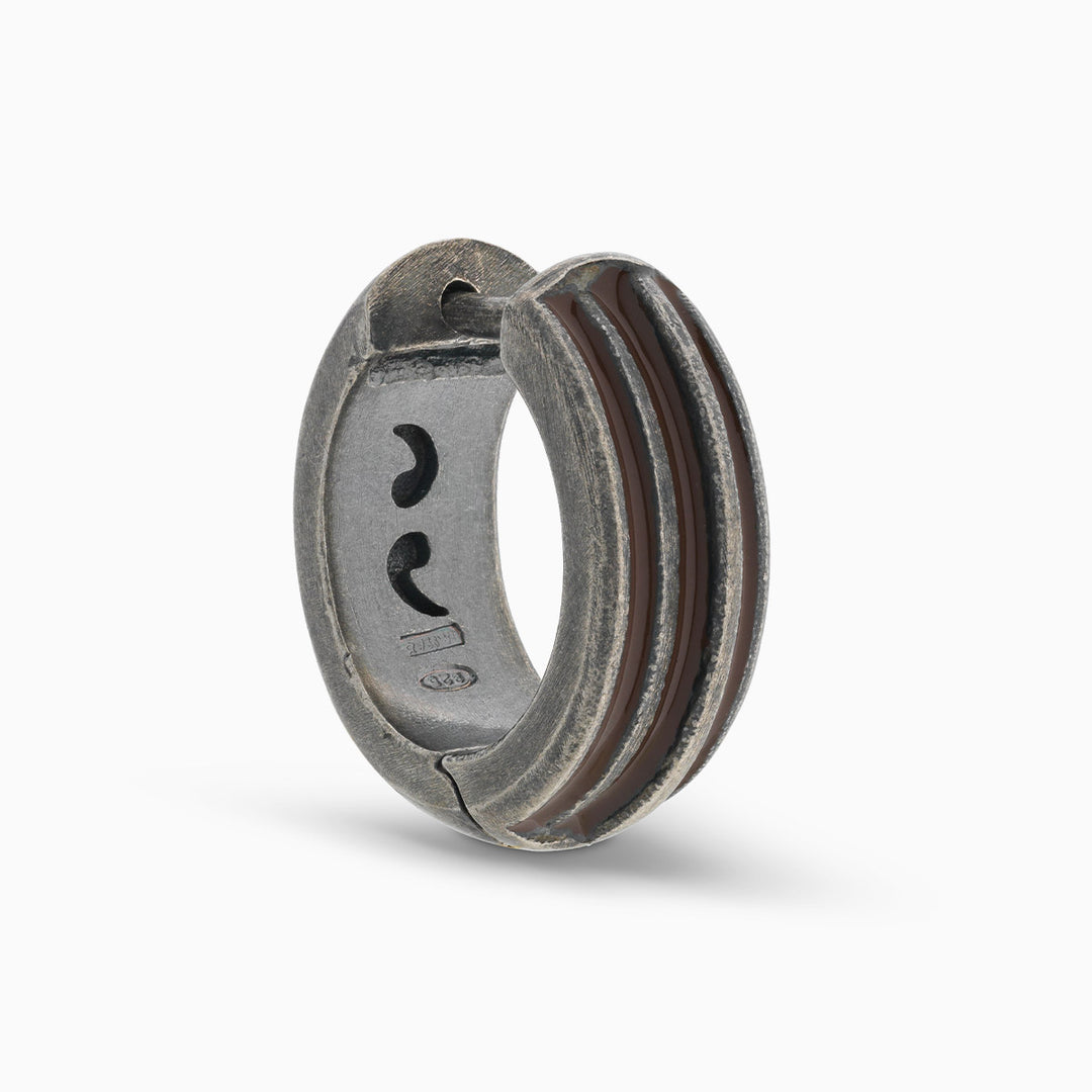 MARCO DAL MASO ACIES Huggie Earring in oxidized silver with brown enamel stripes, featuring a curved hoop design, shown in an angled product view against a light background.