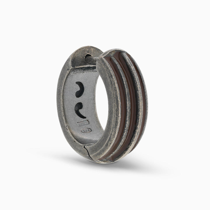 MARCO DAL MASO ACIES Huggie Earring in oxidized silver with brown enamel stripes, featuring a curved hoop design, shown in an angled product view against a light background.