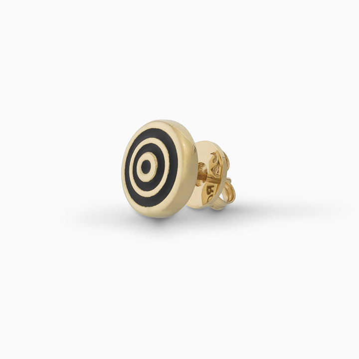 MARCO DAL MASO Acies Ipnotic Earring in yellow gold with black enamel, featuring a circular stud design with concentric gold and black rings, shown in an angled product view against a light background.