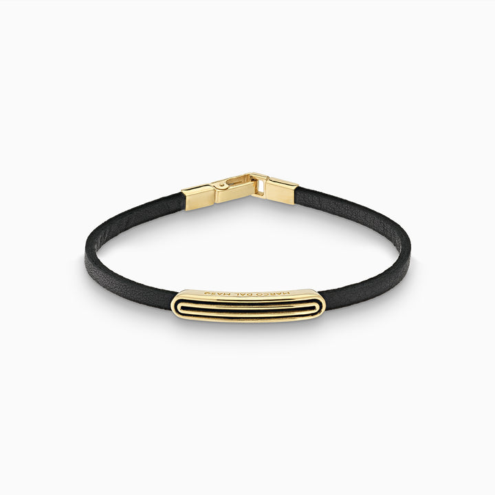 Leather band in dark leather and gold plating on a clean studio floor.
