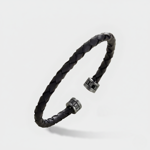 Acies Collection cuff in woven black leather and dark stone-set metallic caps floating above a soft shadow.