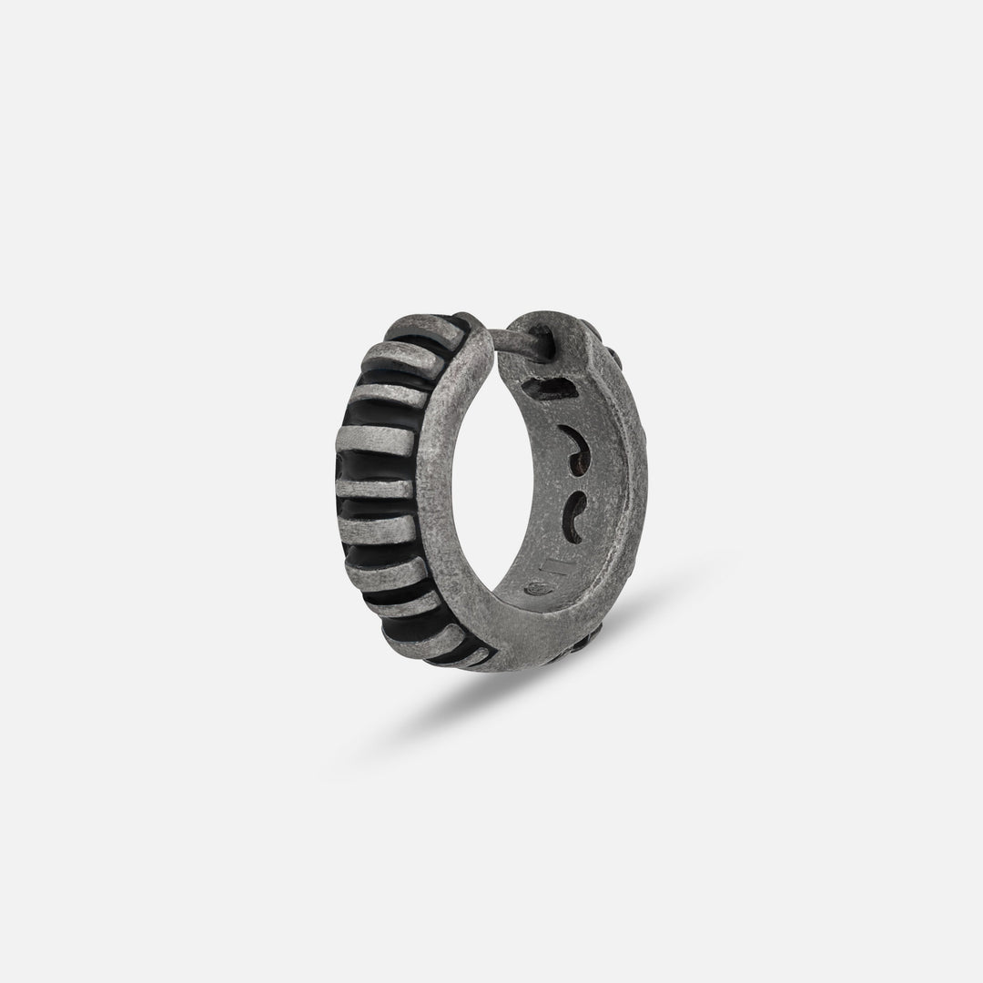 MARCO DAL MASO Acies Mini Hoop Earring in oxidized silver with black enamel detailing, featuring a ribbed hoop design, shown in an angled product view against a light background.