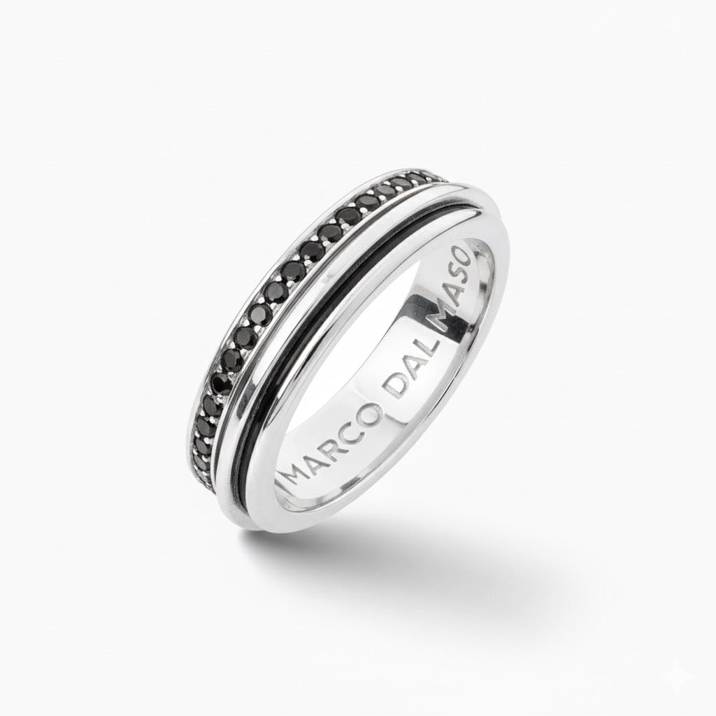 Spin ring in polished metal and paved gems on a minimalist stage.
