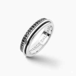 Spin ring in polished metal and paved gems on a minimalist stage.