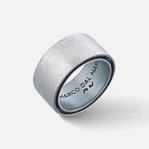 Angled view of wide band revealing brushed silver and branding on white plane.