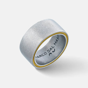 Wide band ring in matte silver with yellow inner groove on white background.
