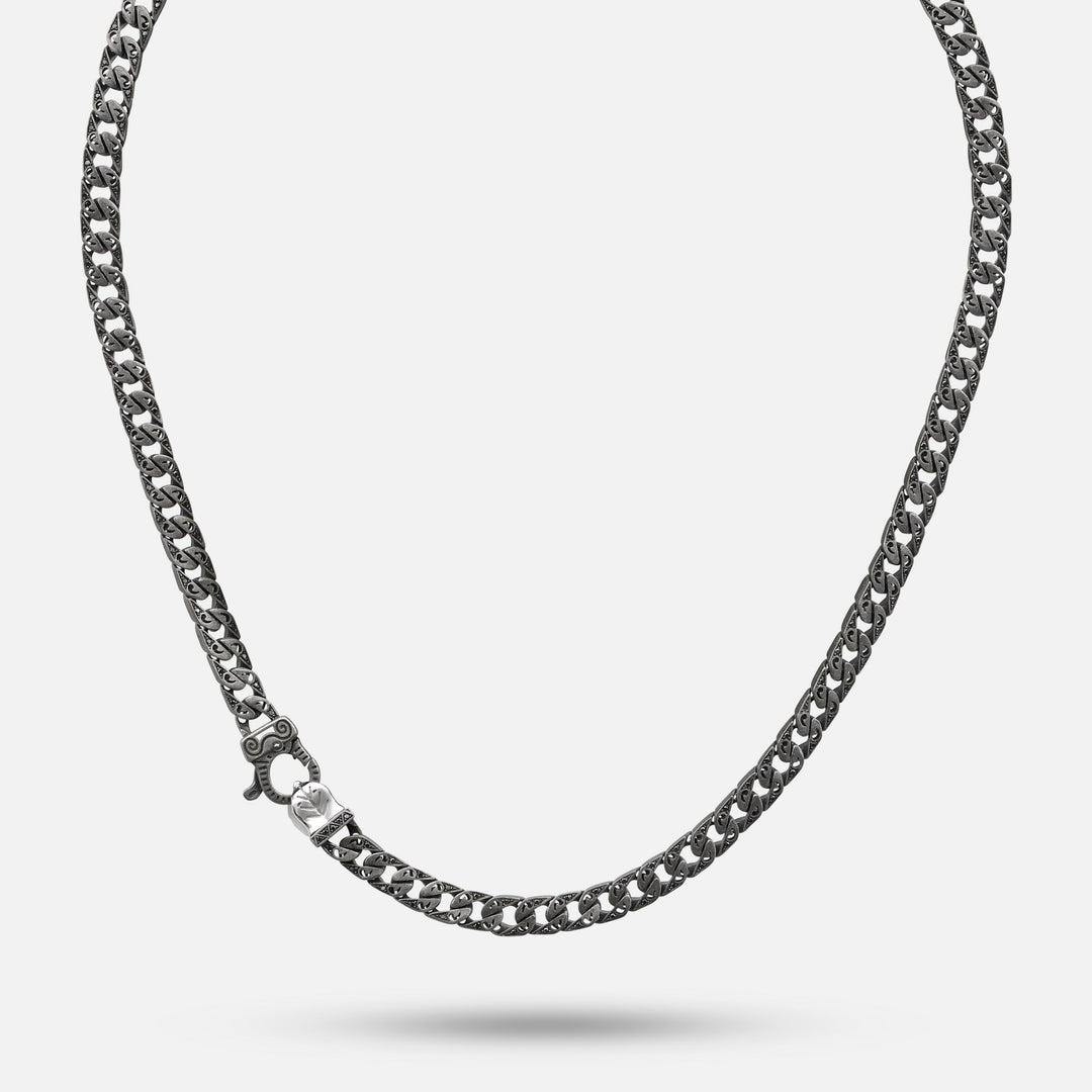 Full view of a dark necklace with ornate repeating links.