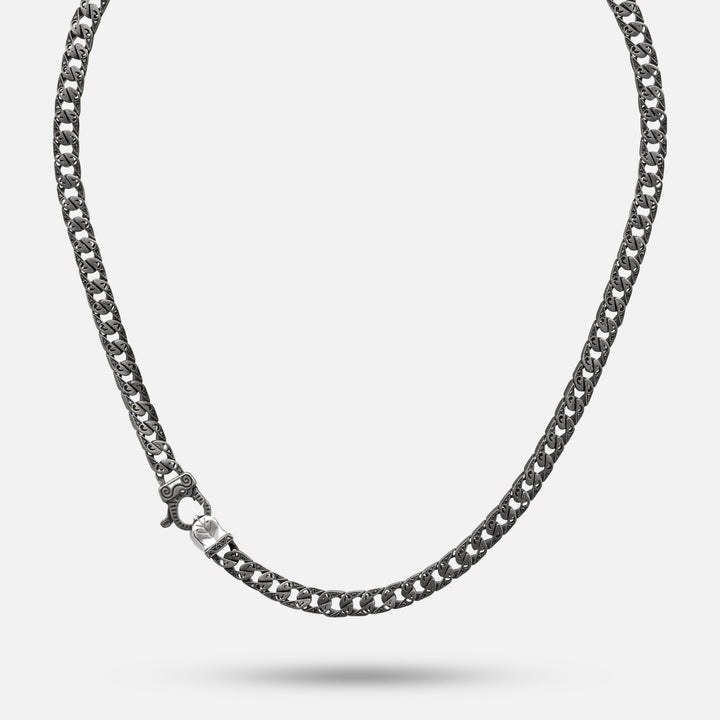 Full view of a dark necklace with ornate repeating links.