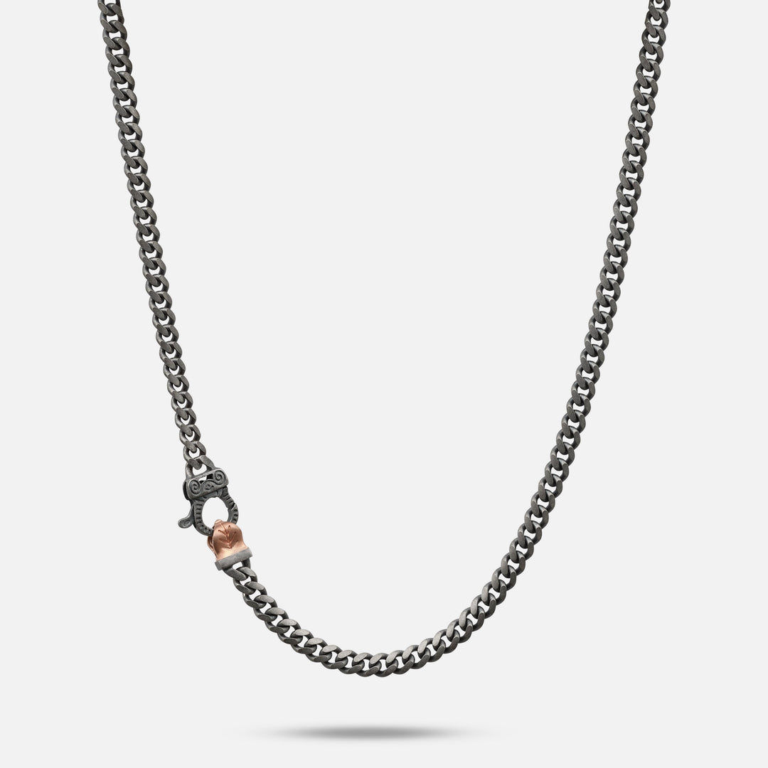 Dark chain necklace with a rose-gold clasp detail.