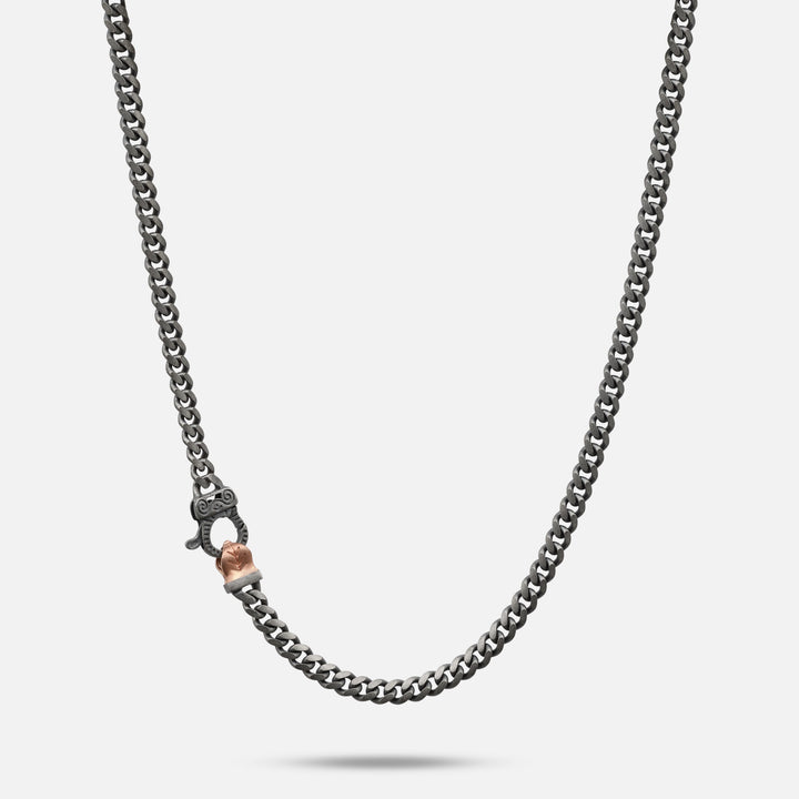 Dark chain necklace with a rose-gold clasp detail.