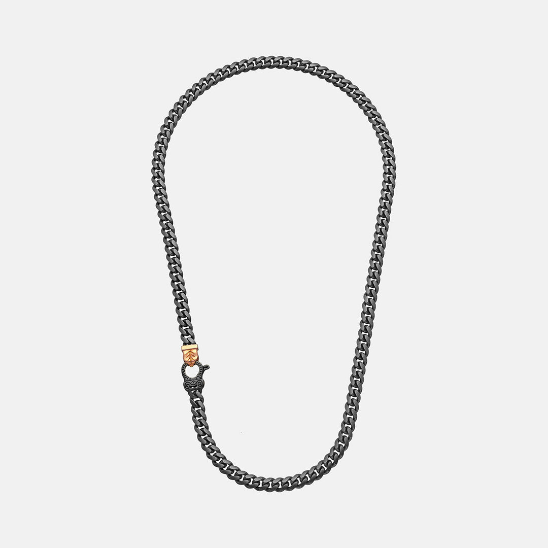 Curb necklace in dark metal featuring dual-tone clasp on neutral backdrop.