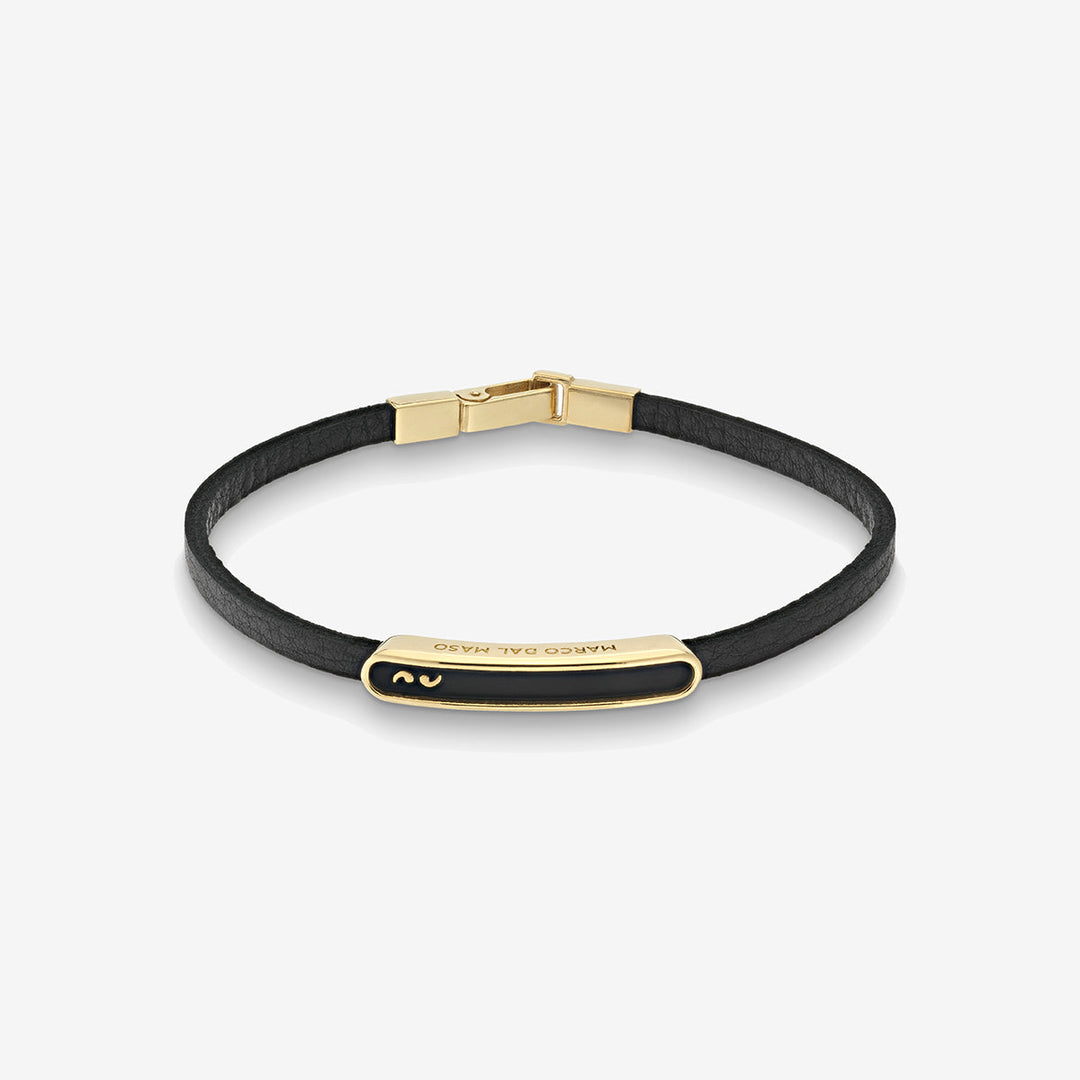 Overhead shot of leather cord bracelet displaying gold bar and black inlay.