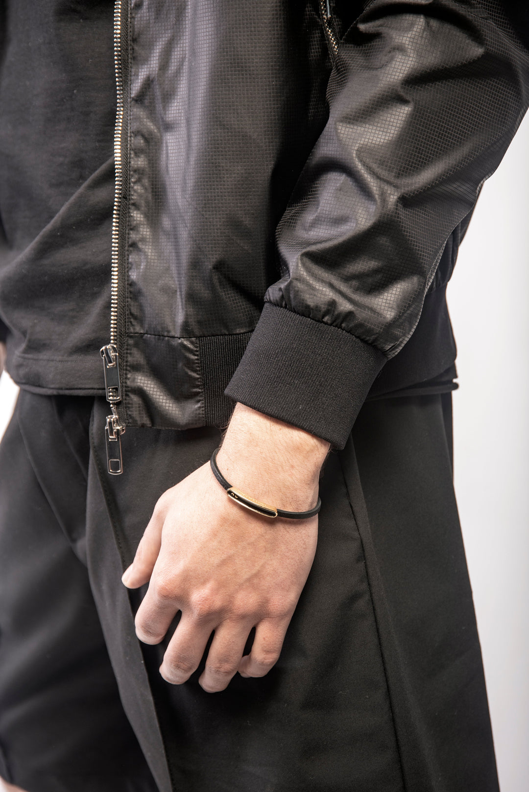 Close-up view of wrist wearing dark band and black jacket with zipper.