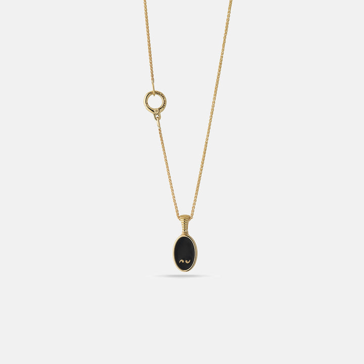 Pendant necklace in yellow gold featuring black oval stone and round clasp.