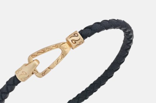 MARCO DAL MASO LASH Braided Bracelet in black leather with a decorative yellow gold vermeil clasp, shown in a close-up product view against a light background.