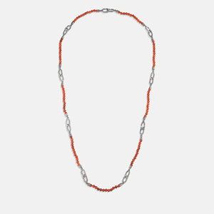 Beaded chain in coral stones and silver metal on white stage.