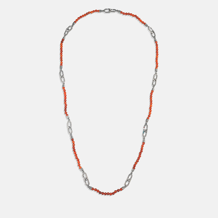Beaded chain in coral stones and silver metal on white stage.