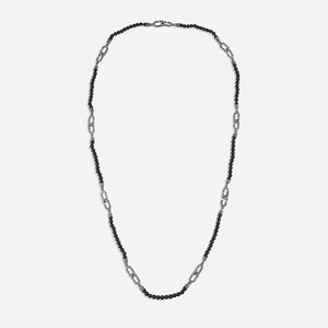 Beaded cord in onyx stones and metal links upon plain floor.