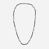 Beaded cord in onyx stones and metal links upon plain floor.