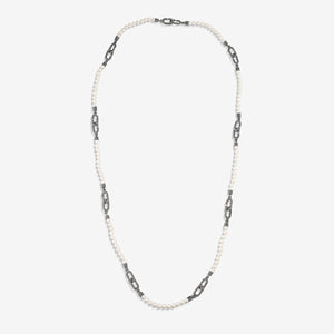 Pearl strand in white pearls and dark links on studio backdrop.