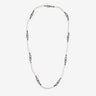 Pearl strand in white pearls and dark links on studio backdrop.