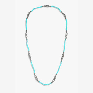Long necklace in turquoise beads and link hardware on white backdrop.