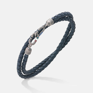 Double-wrap bracelet in dark blue leather and metal on a pale floor.