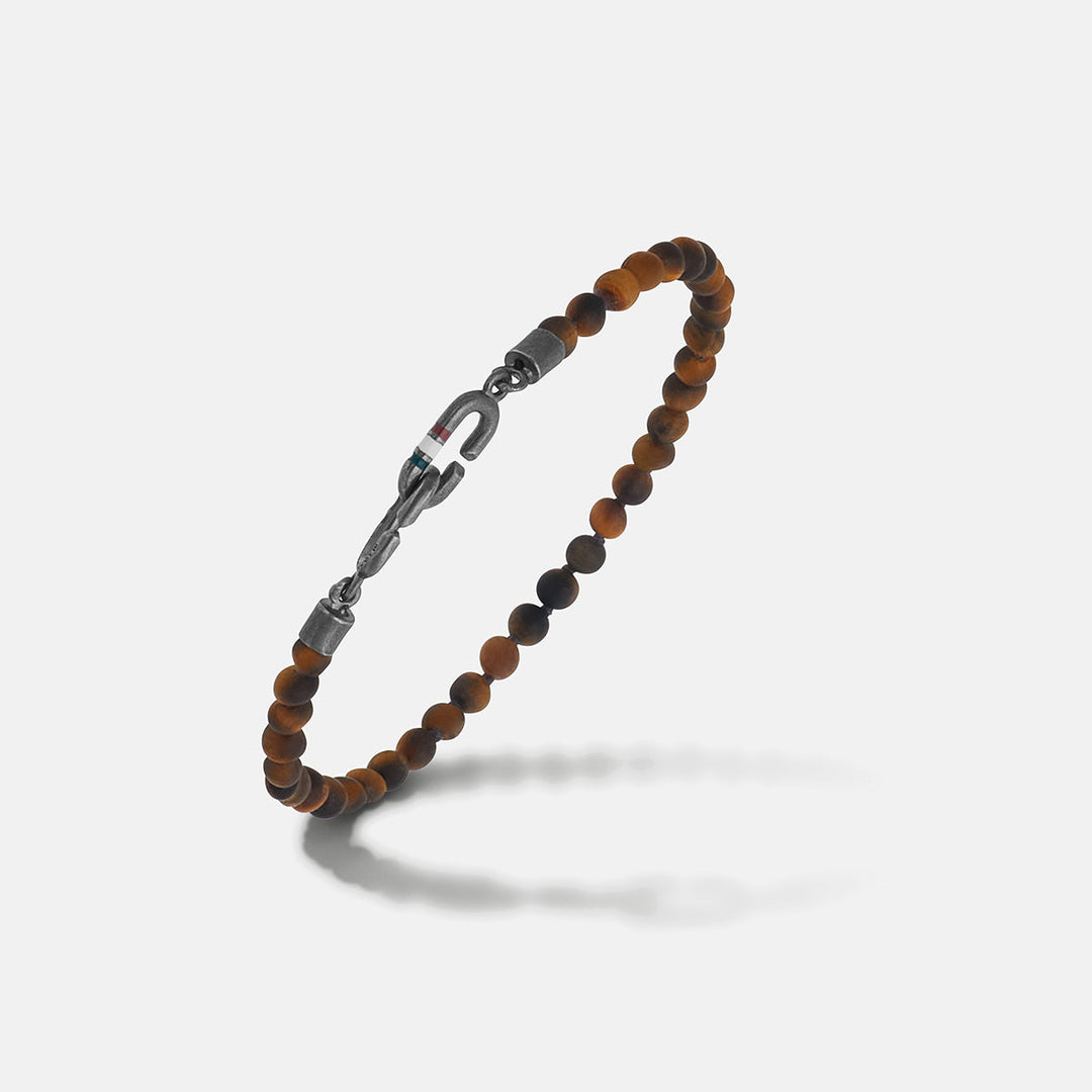 Tiger's eye bracelet in brown beads and iron on a bright studio floor.