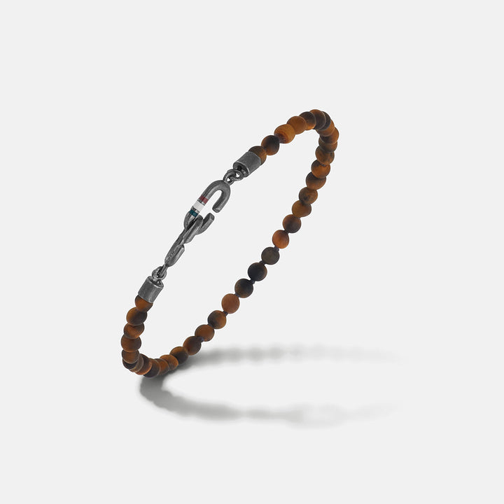 Tiger's eye bracelet in brown beads and iron on a bright studio floor.
