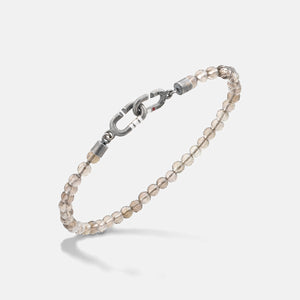 Smoky quartz band in translucent stones and iron on an off-white plane.