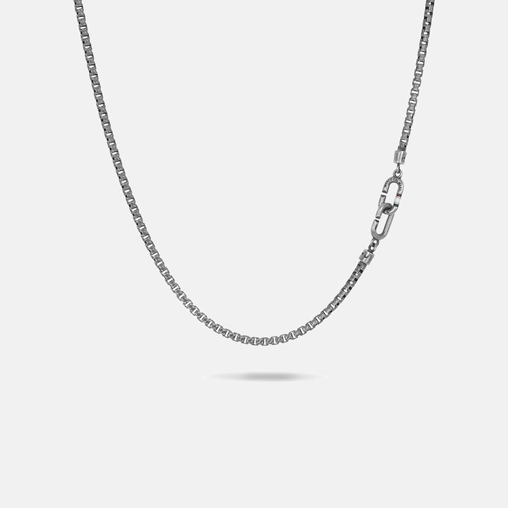 Link chain in oxidized silver featuring clasp detail over neutral space.