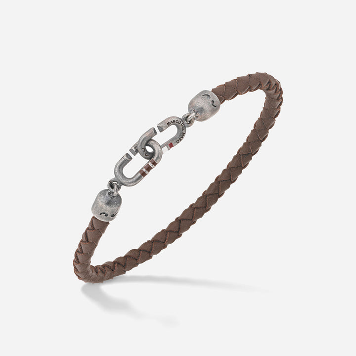 Woven bracelet in brown leather and antique silver on a soft backdrop.