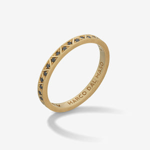 Slim ring in bright metal and dark stones on a gradient studio stage.