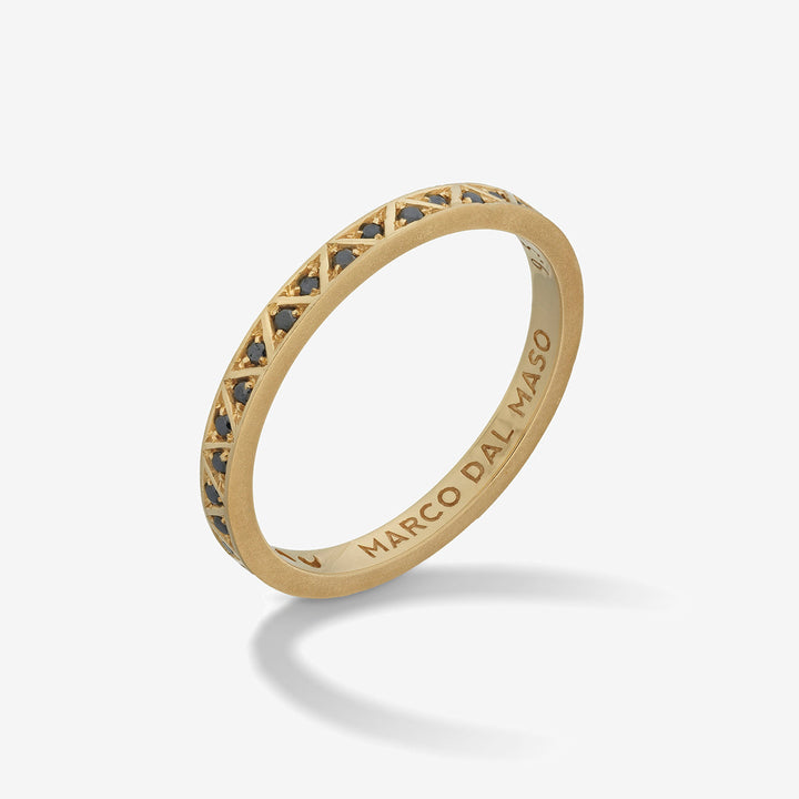 Slim ring in bright metal and dark stones on a gradient studio stage.