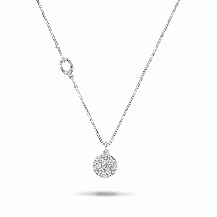 A silver chain necklace featuring a circular pavé pendant and a matching oval clasp, displayed on a clean white background with a soft shadow underneath.