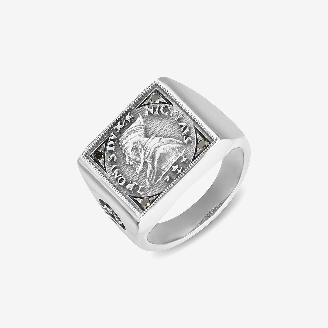 Signet ring in polished silver and coin motif on clean surface.