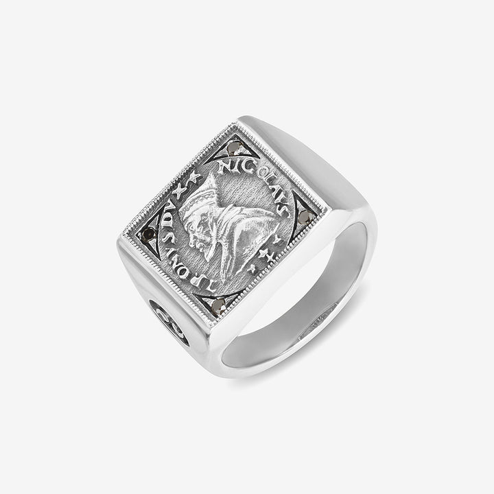 Signet ring in polished silver and coin motif on clean surface.