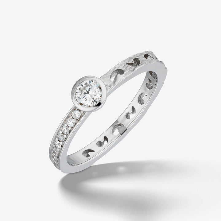 MARCO DAL MASO Orion Gemstone Ring in white gold with white diamonds, featuring a round central diamond, smaller diamond accents, and a textured band, shown in an angled product view.