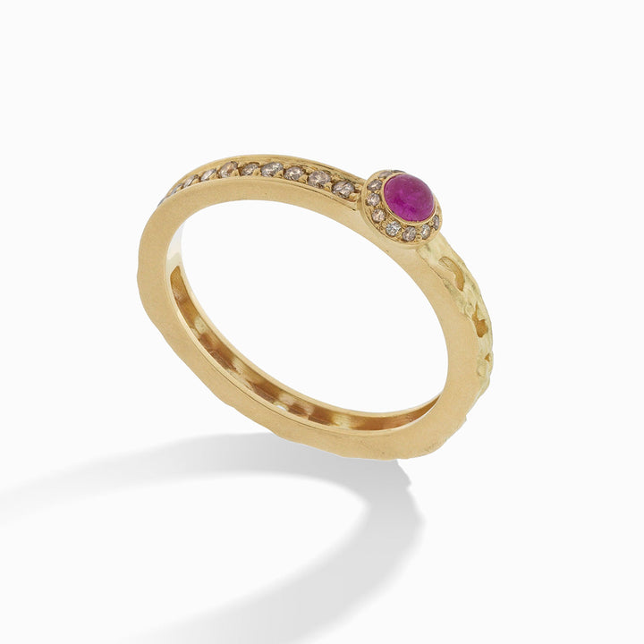 MARCO DAL MASO Orion Oval Gemstone Ring in yellow gold, featuring an oval pink sapphire surrounded by champagne diamonds and a textured gold band, shown in an angled product view.